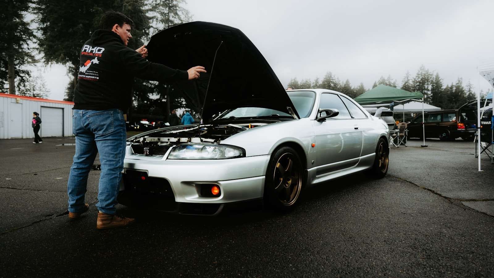 A person inspecting a car's engine with the hood open